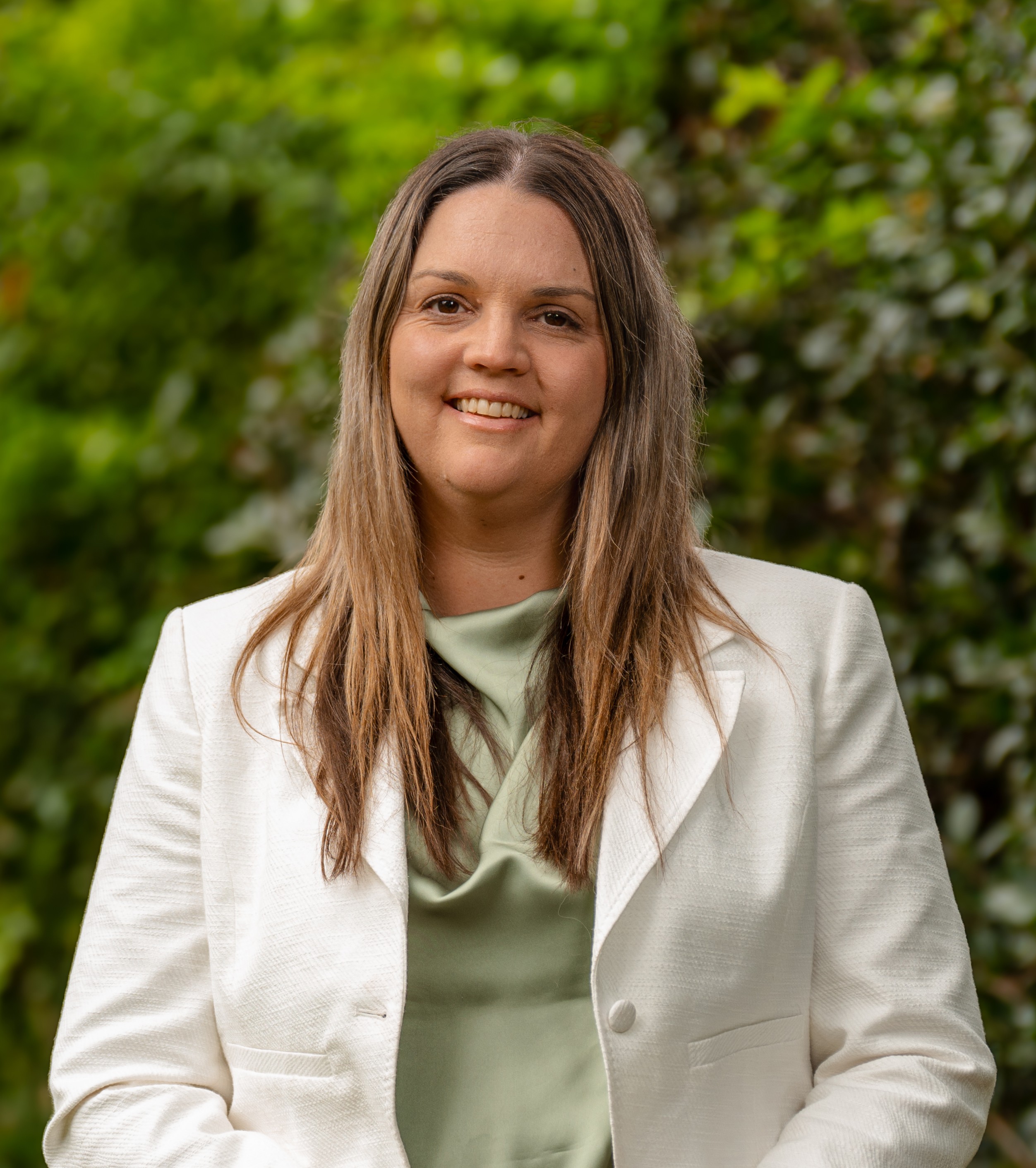 Sarah Luscombe in front of a green leafy background