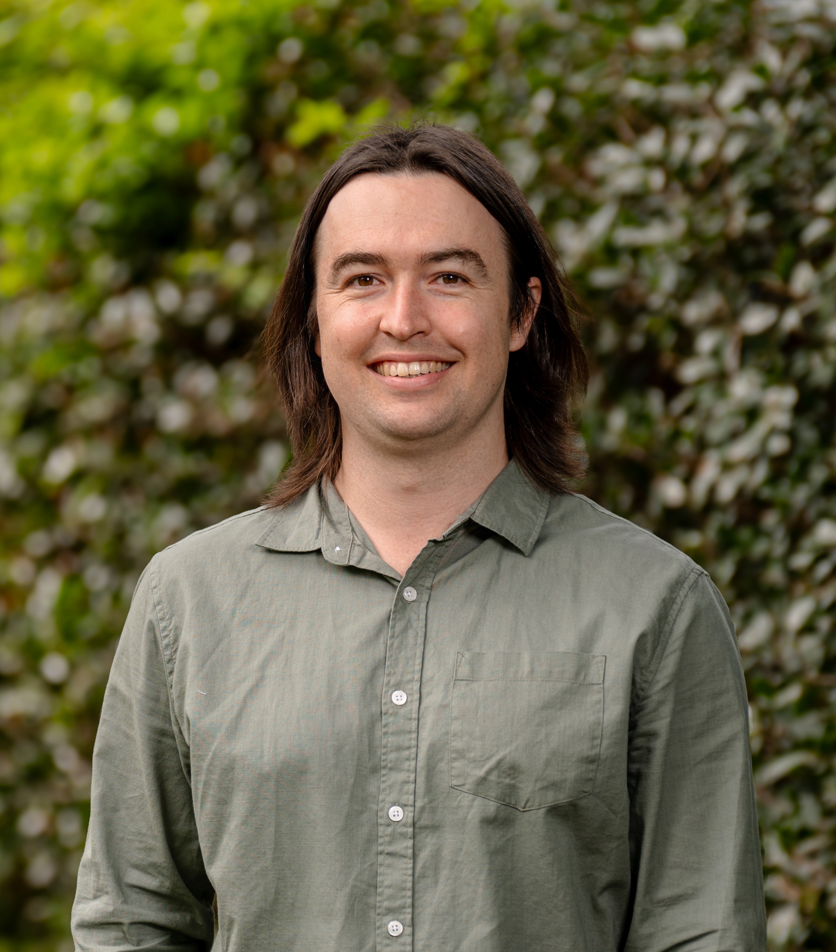 Matthew Wright in front of a green leafy background