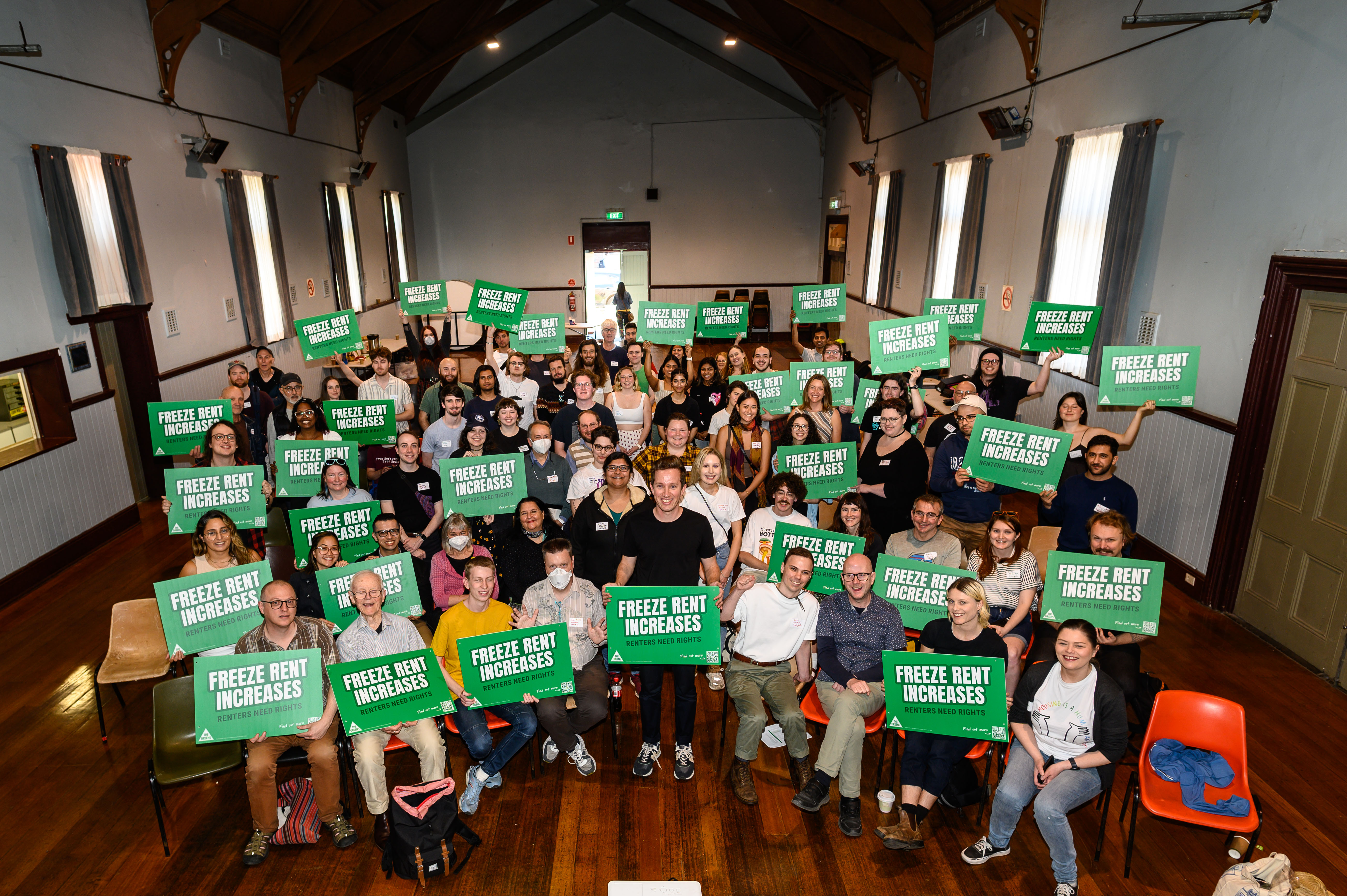 Renters doorknock weekend of Action in Melbourne, Max Chandler-Mather with 100 volunteers smiling, holding rent freeze now signs