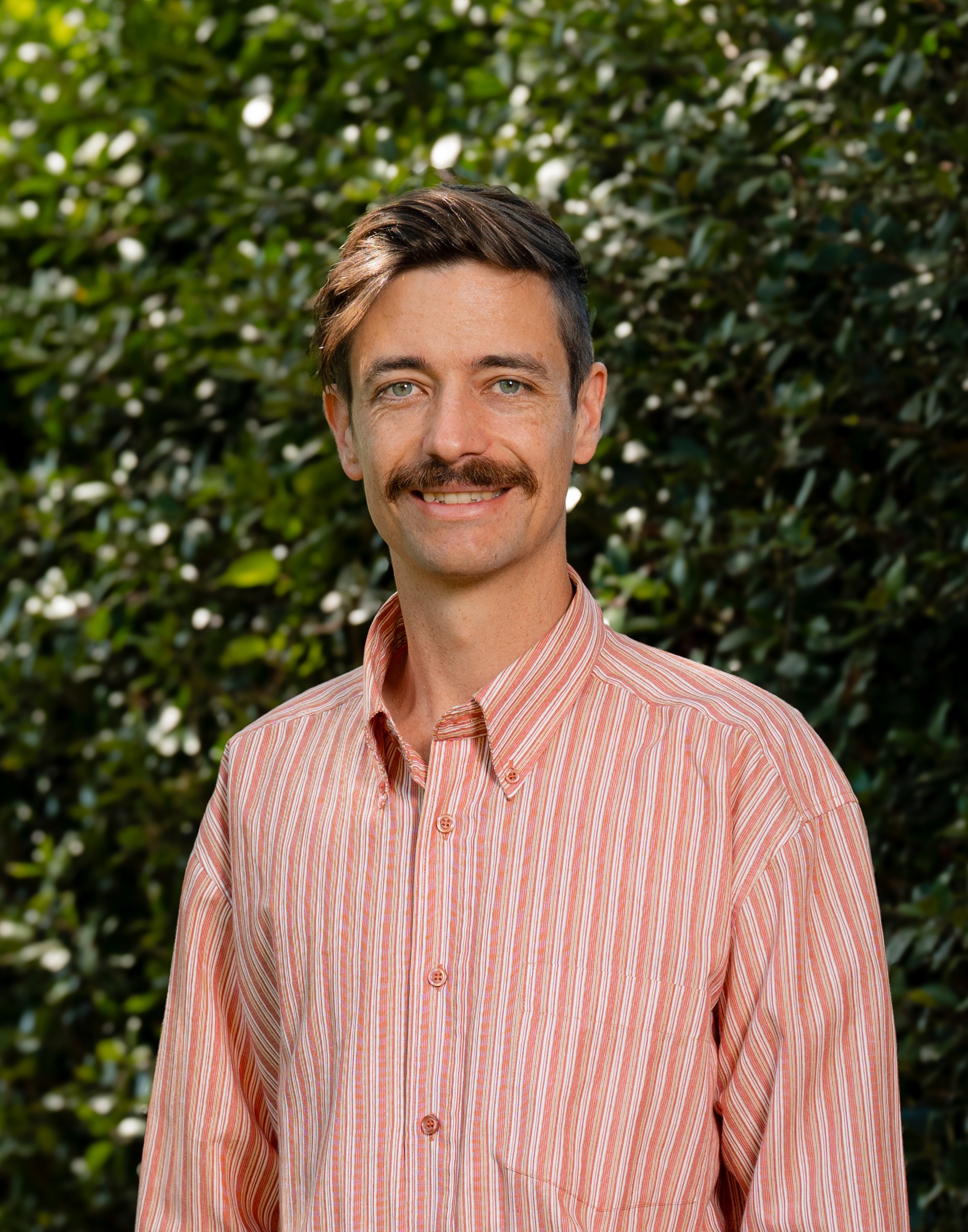 Chris Smith in front of a green leafy background