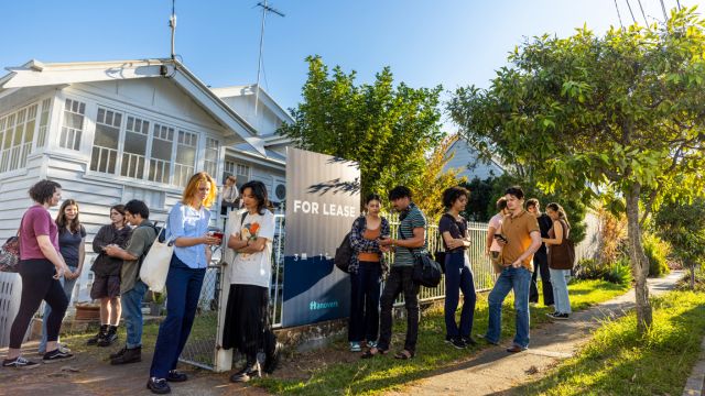 A long list of people wait outside a home for a rent inspection