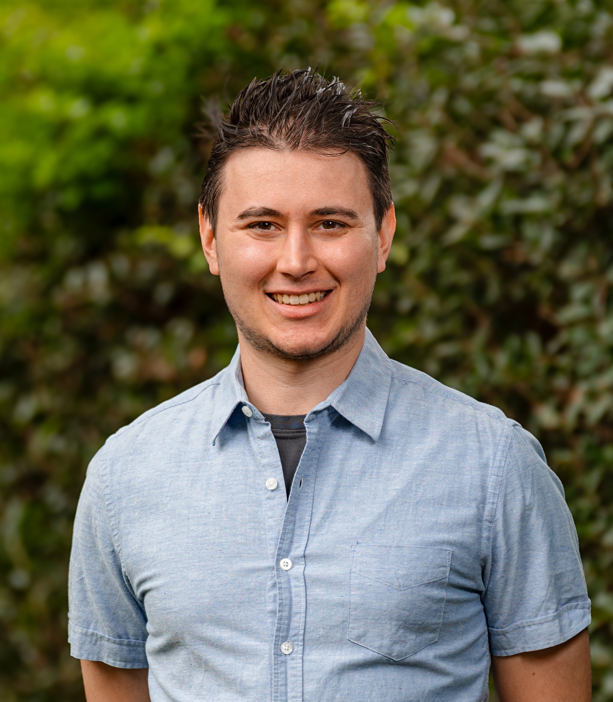 John Photakis in front of a green  leafy background