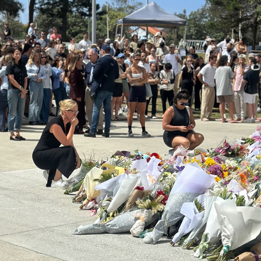 Larissa Waters visits Bondi Beach to pay her respects after the terrorist attack. Picture of her looking over a large amount of flowers. 