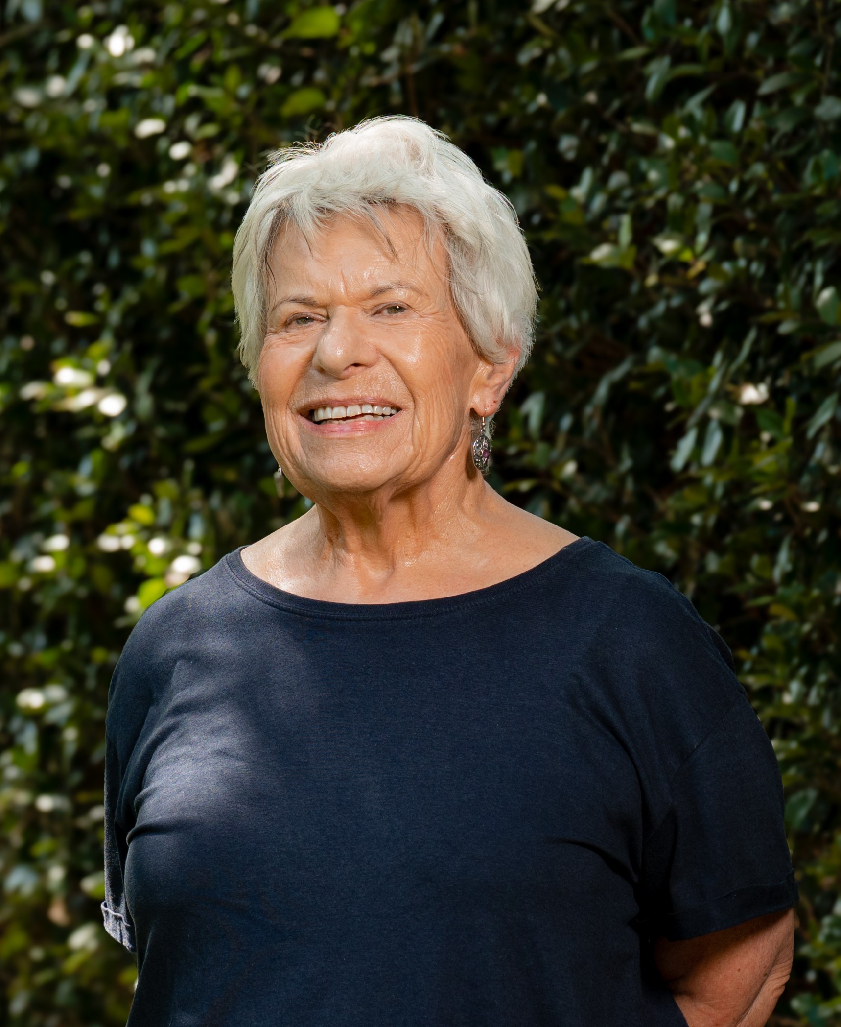 Helen Wright standing in front of a green, leafy background