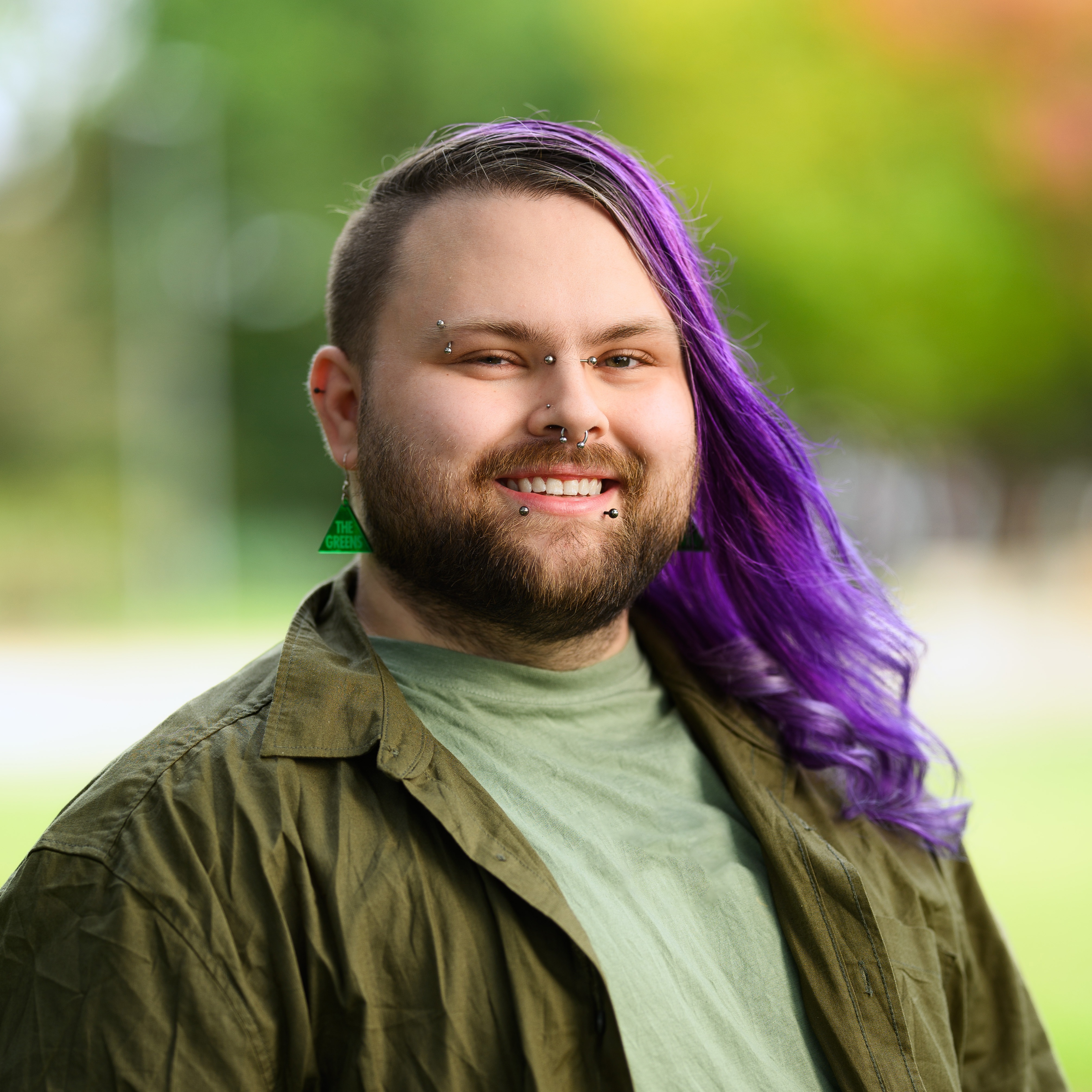 A smiling person with long purple hair