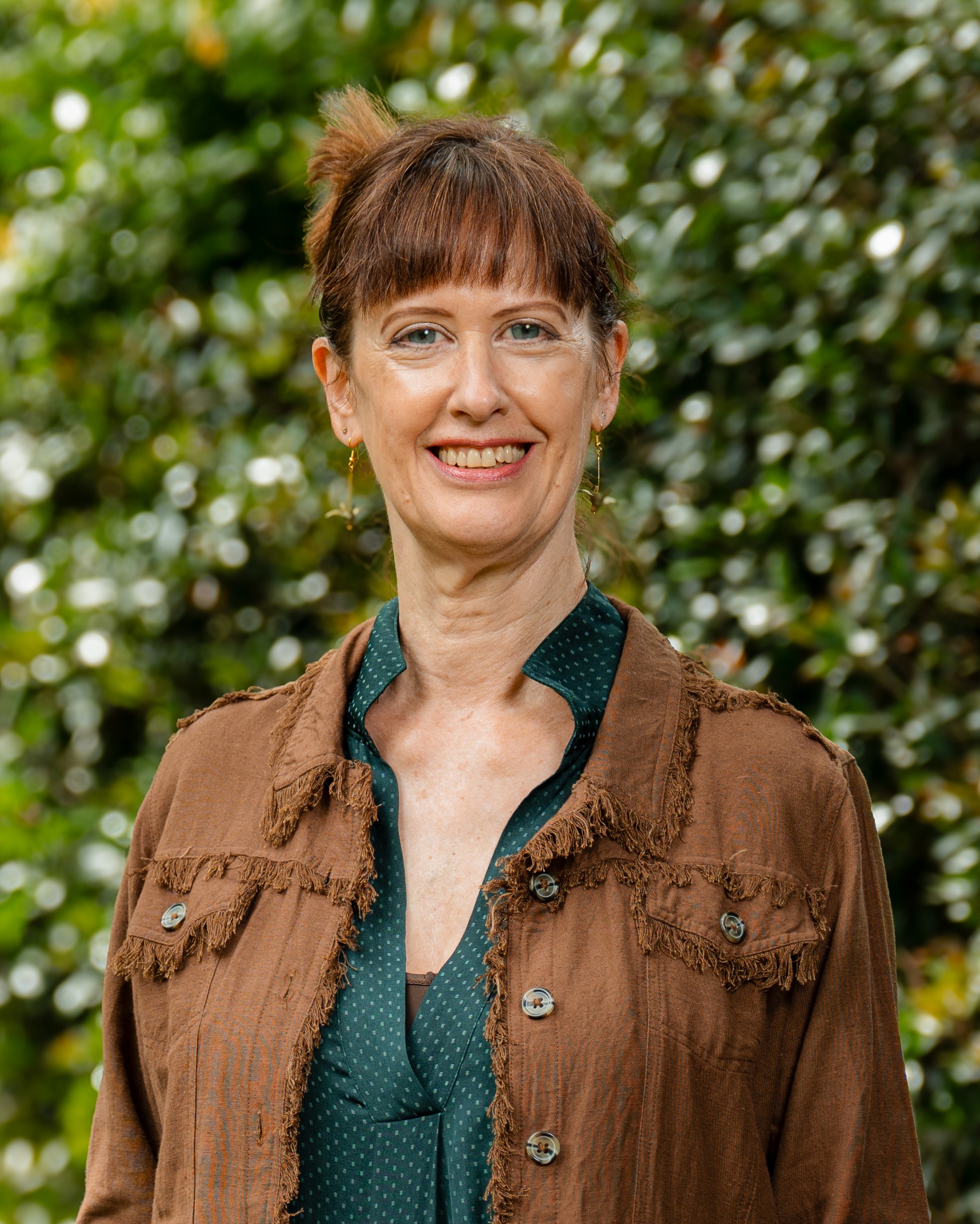 Jenn Tranter in front of a green, leafy background