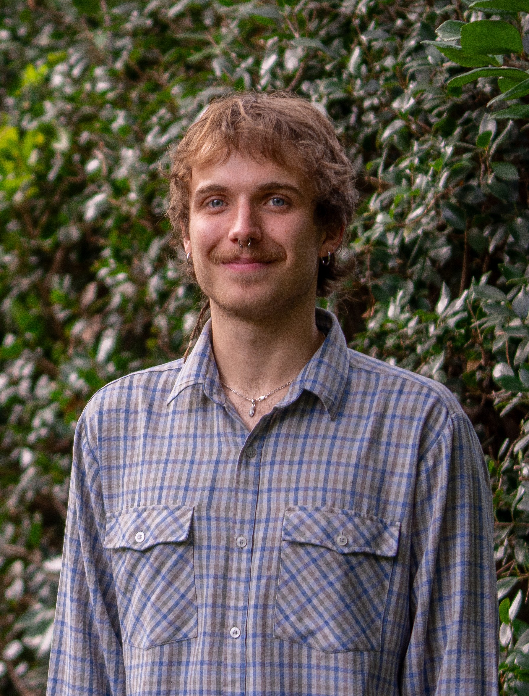 Alex Taylor in front of a green leafy background