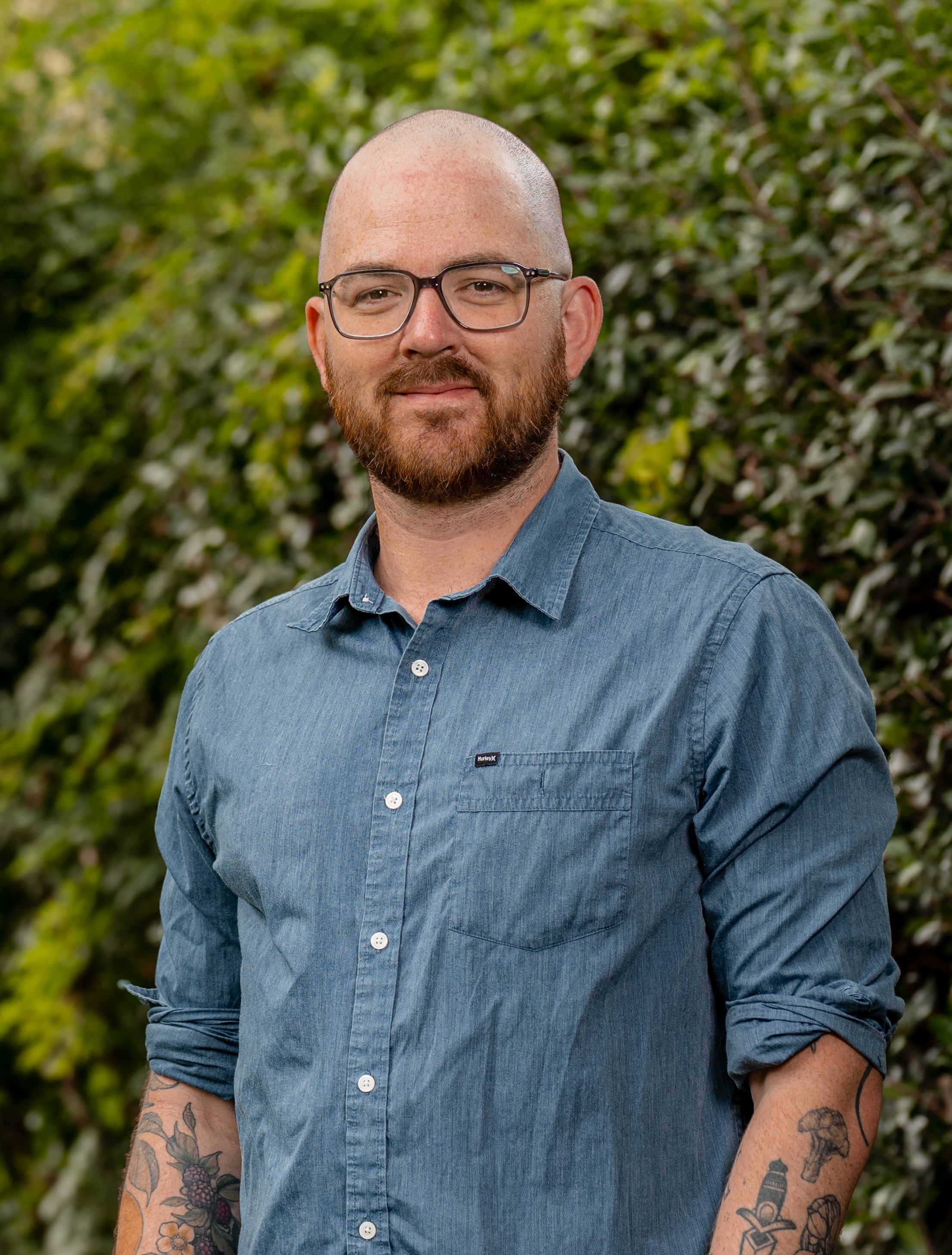 Sam Tyler in front of a green, leafy background