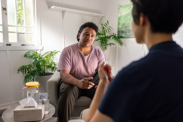 A man speaks to a therapist in a pleasant office