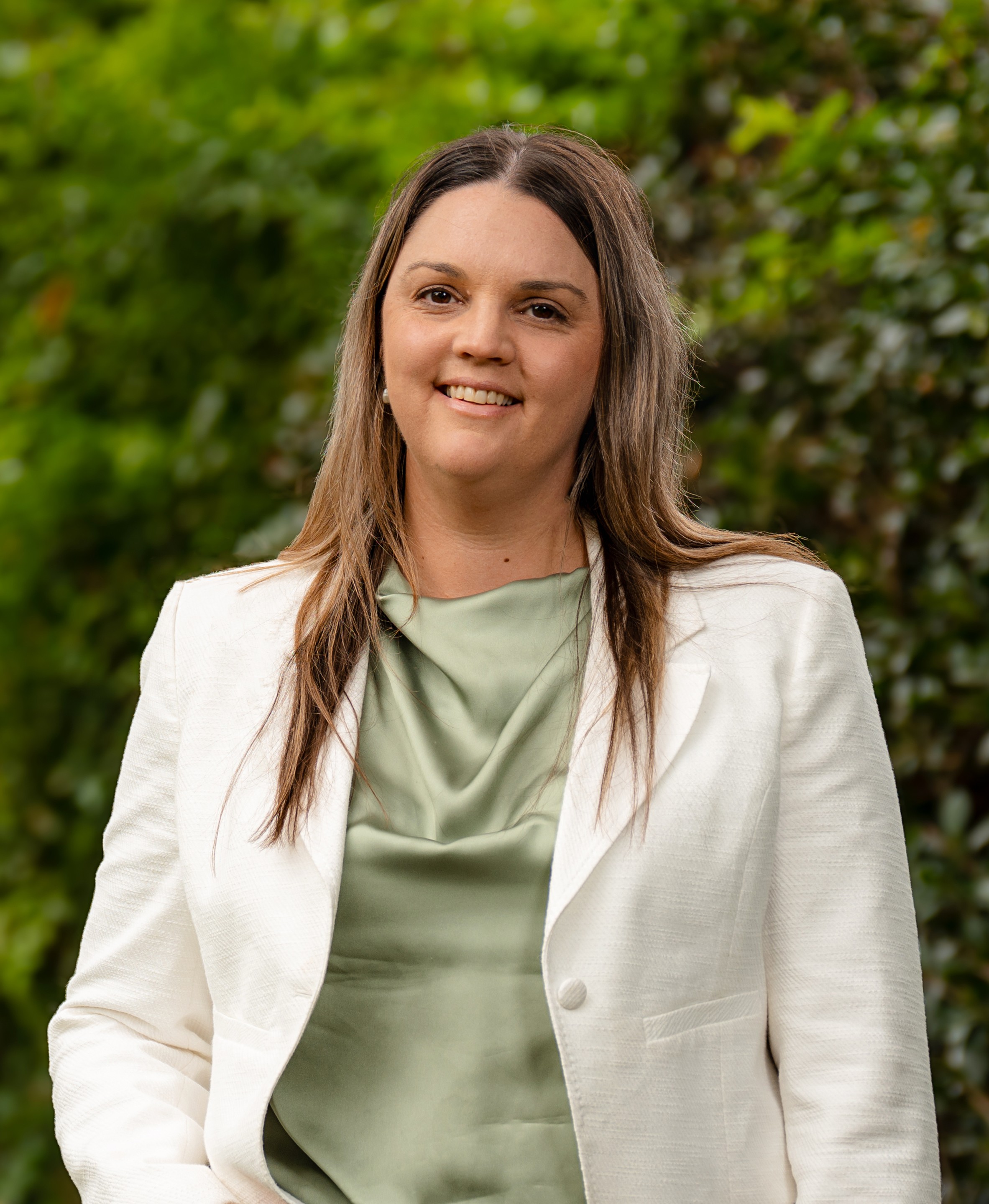 Sarah Luscombe in front of a green leafy background