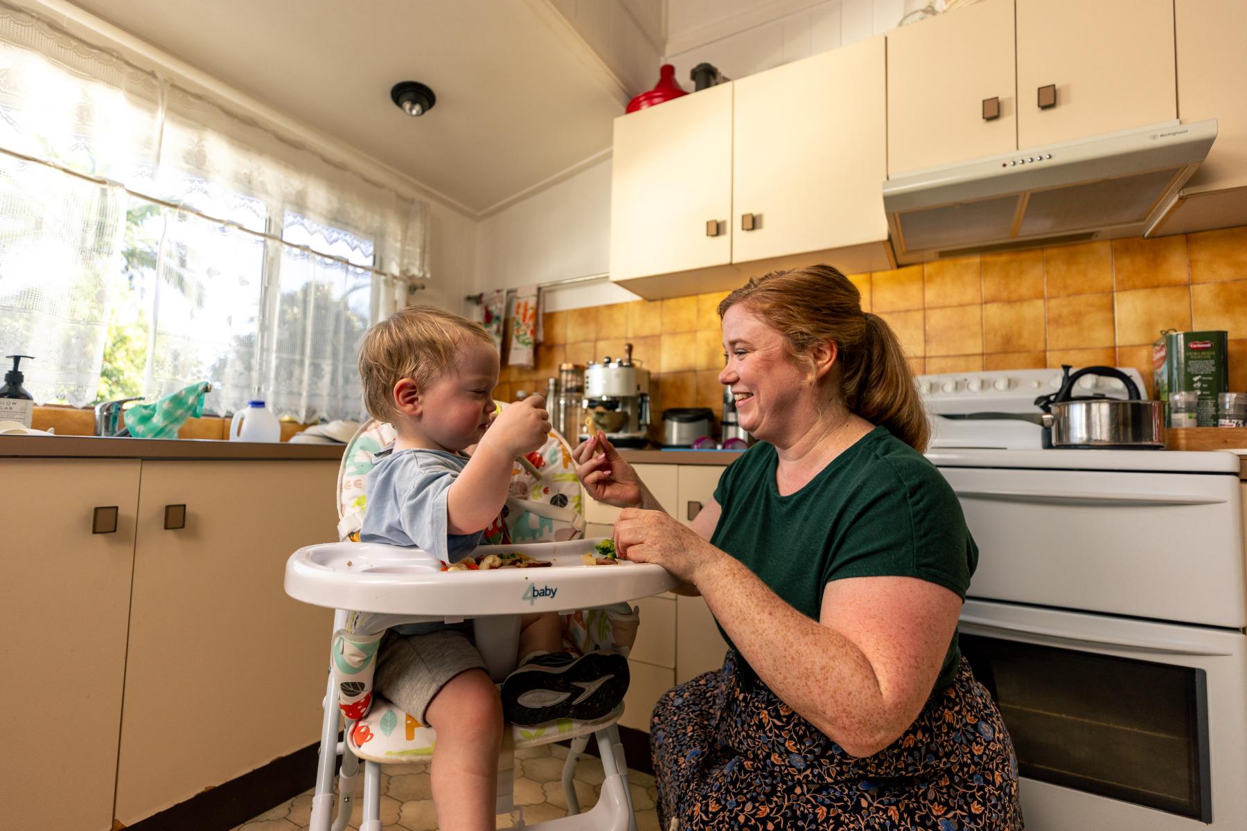 Woman feeding baby in a highchair in the kitchen