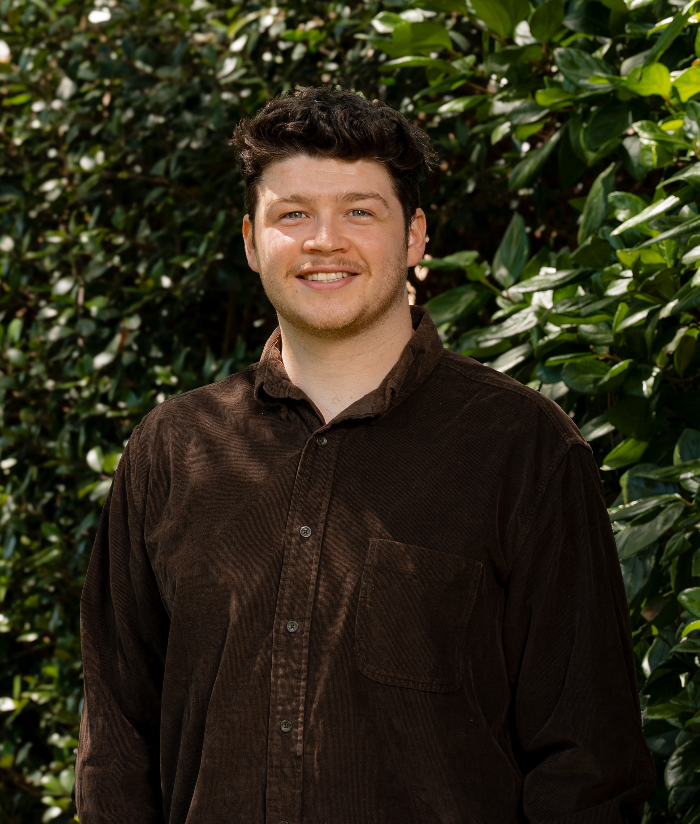 Samuel Moore in front of a green leafy background