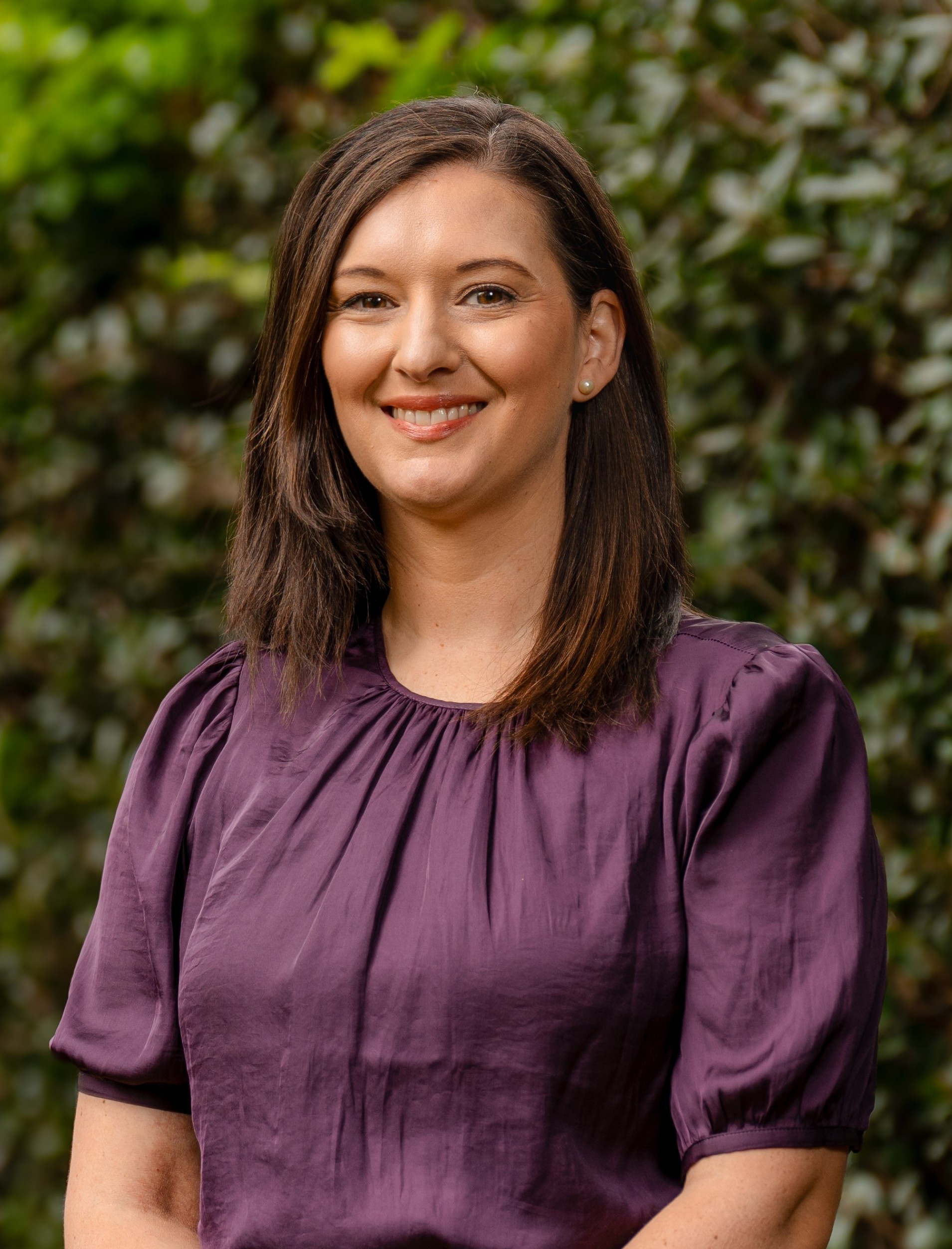 Melanie Searle in front of a leafy green background